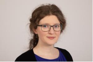 An image of the Chair, Jago Williams, a woman with brown hair and blue glasses.
