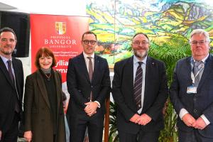 Senior leaders standing in fron to Bangor University banner gathering for PHarmacy launch
