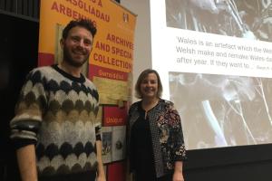 Two people stand either side of a yellow and red banner which reads 'Archives and Special Collections' 