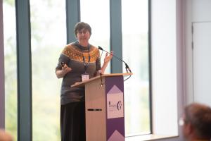 Dr Rebecca Payne, GP, Clinical Senior Lecturer at Bangor University is speaking at a lectern 