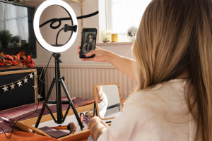 A woman holding a phone in front of a selfie ring light