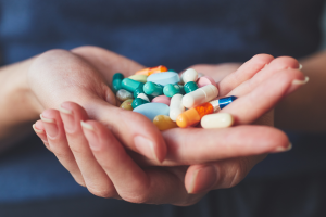 Lots of different coloured pills in someone's hand