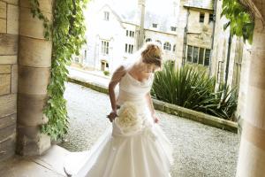 A bride in a wedding dress is standing in the archway of Bangor University's Inner Quad 