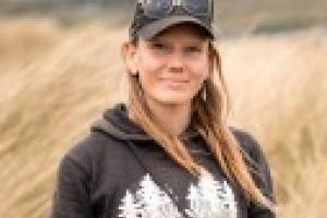 Portrait image of Kara Moses standing in a field, smiling.