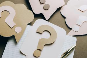 Question Marks on paper on top of a lined notebook