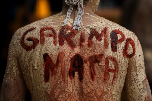 An Indigenous man with a phrase in Portuguese painted on his back 
