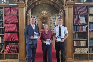 North Wales PCC Andy Dunbobbin, Professor Martina Feilzer and Gareth Parry, Optimisation Programme Inspector standing in a library 