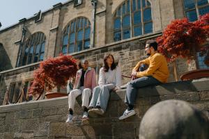 Students sitting on a wall outside a university building 