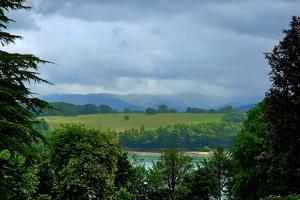 Llun yn dangos caeau, coed a mynyddoedd dros Afon Menai