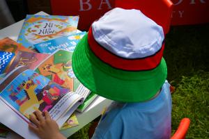 Small child wearing a hat reading books