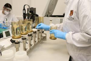 Two scientists in white coats examining water samples in a lab 