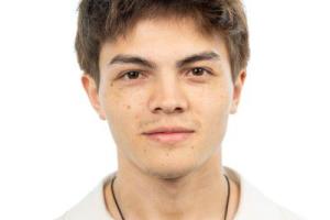 an image of a student (luke) looking at the camera with a small smile. the student is in a white background, and is wearing a white shirt