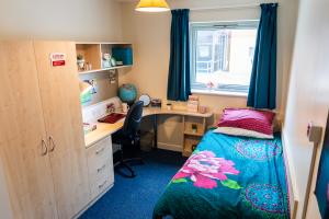 Ffriddoedd modern en-suite with a bed, desk, chair, shelves and wardrobe