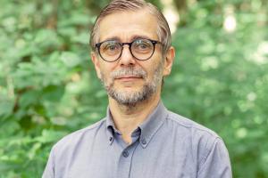 A man wearing glasses standing for a photo