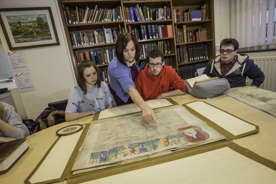 Seminar setting with tutor and students looking at a historic document.