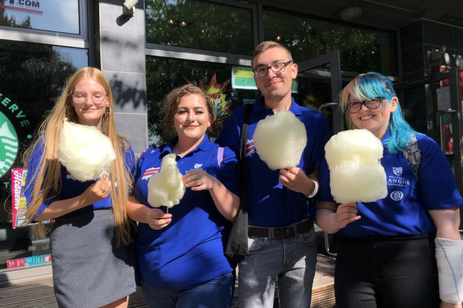 Arweinwyr Cyfoed yn bwyta 'Candy Floss' tu allan i Bar Uno ym Mhentref Ffriddoedd yn ystod Wythnos Groeso