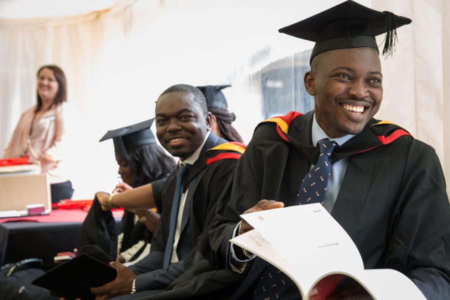 A student in a cap and gown smiling after his graduation ceremony