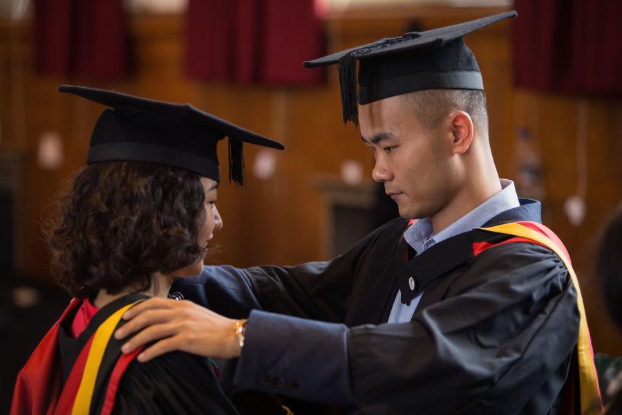 Two students getting ready for their graduation ceremony