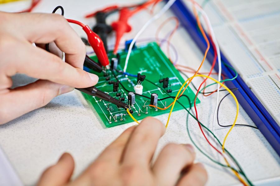 A student using a circuit board and crocodile clips in a computer science and electronic engineering lab 