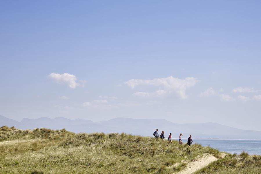 A group of students walking along the beach with the mountains in the background