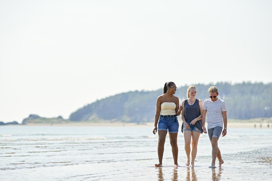 Three students walking along the beach