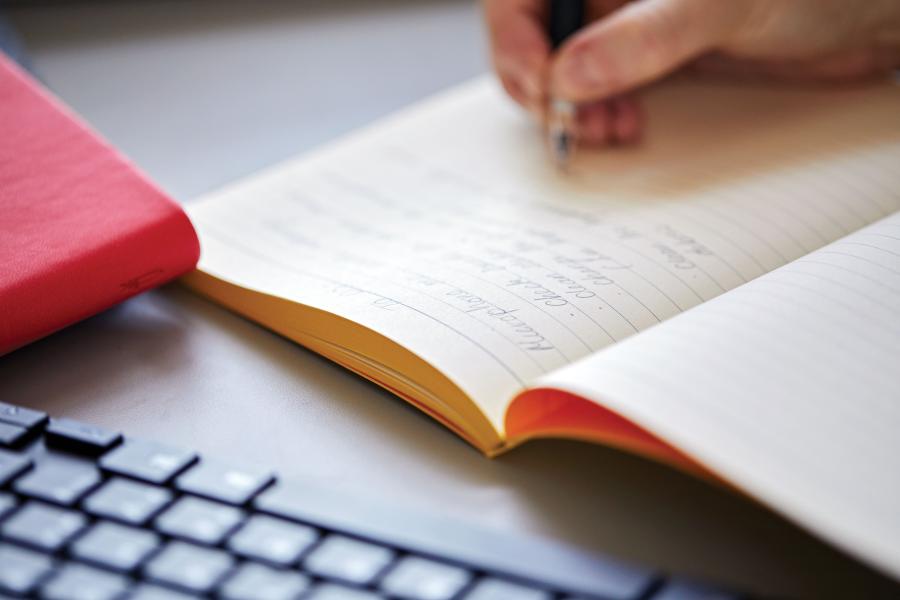 A close up of a student's hand writing notes in a notebook