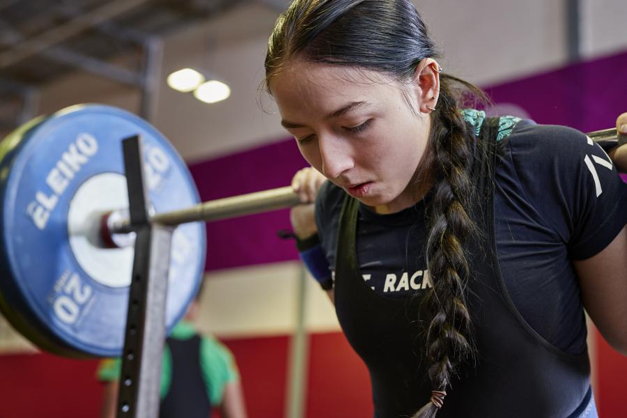 Female student lifting weights using the facilities at the University's Canolfan Brailsford