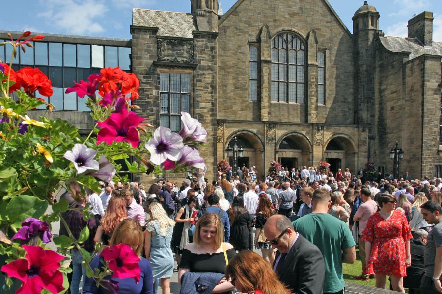 Students and friends and family gather outside the University's Main Arts building on graduation day