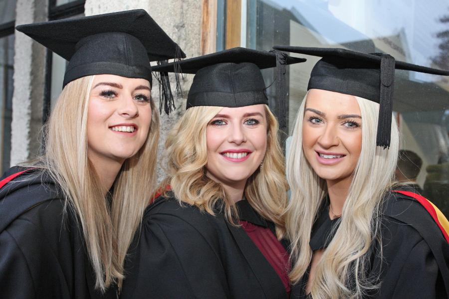 A group of female students smiling to the camera on their graduation day