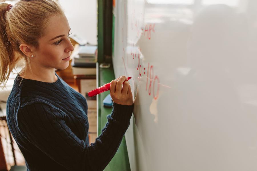 Teacher writing on a white board in the classroom