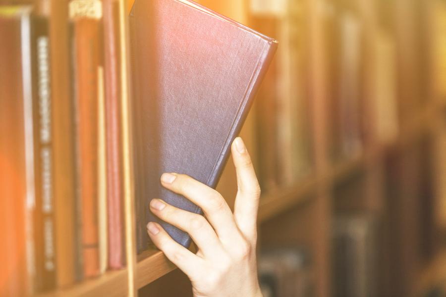 Student taking a book off a shelf.