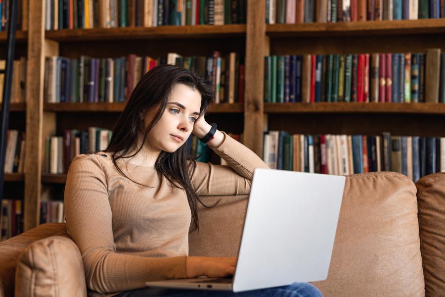 Student sitting in library with laptop