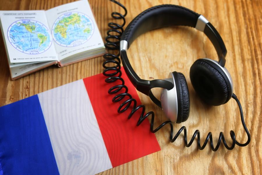 Headphones and book on a desk with a French flag