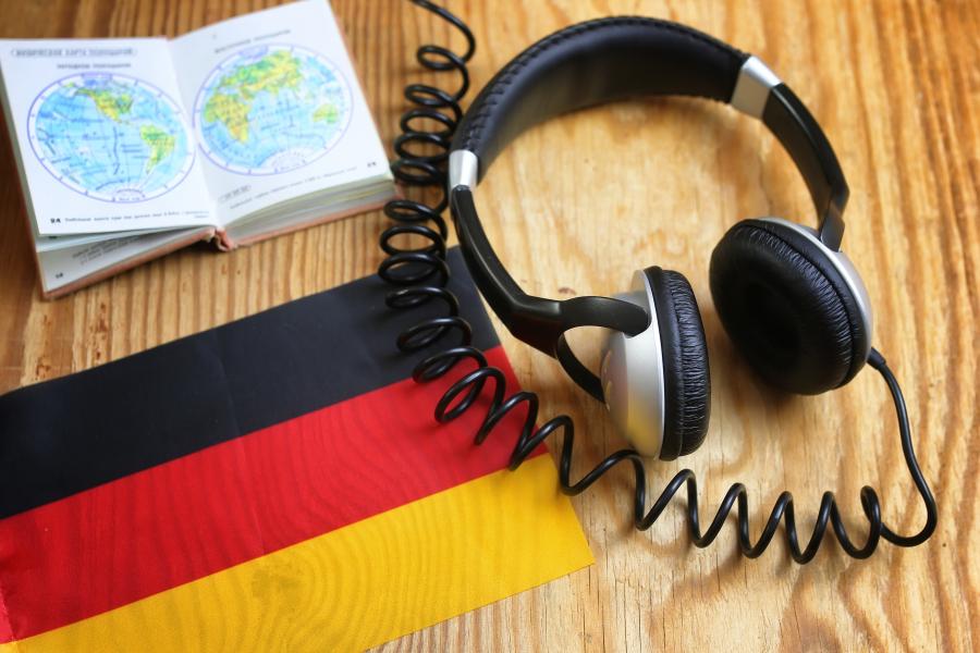 Headphones and book on a desk with a German flag