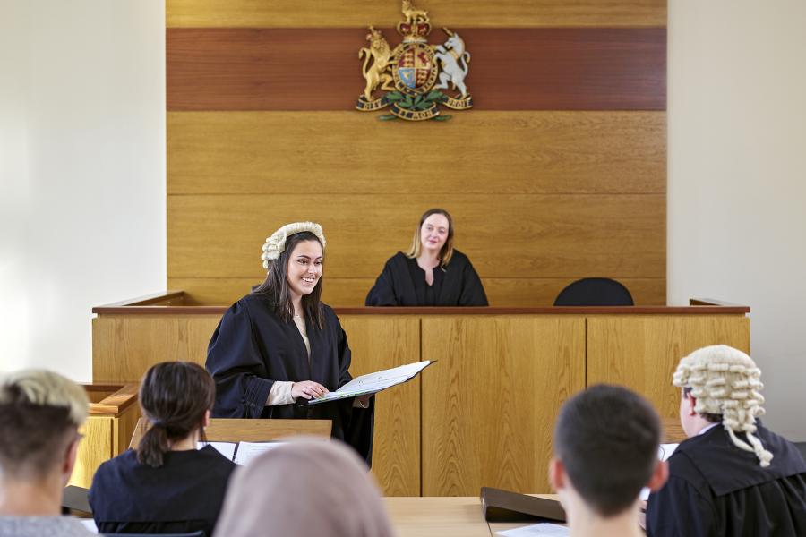 A student wearing a robe and wig in a moot court