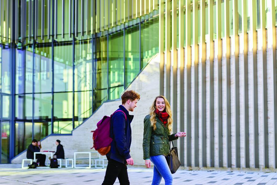 Two students chatting walking outside the Pontio building 