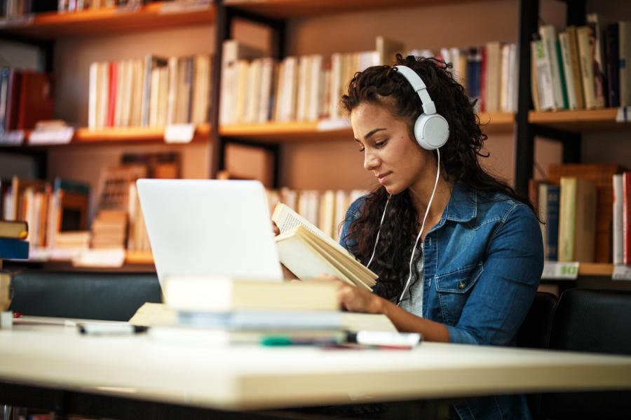 Student listening to headphones while studying in the library