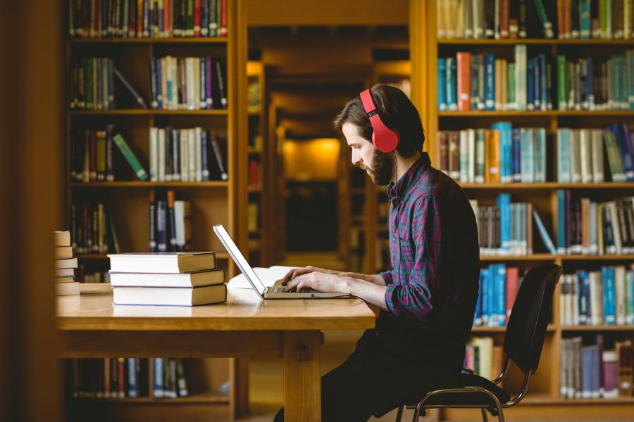 Student studying in the library wearing headphones