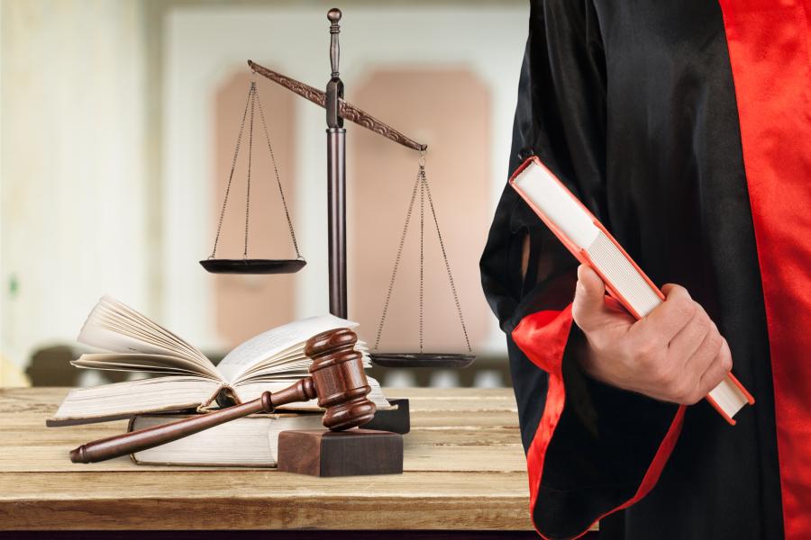 Image of Law student in robe with scales in background