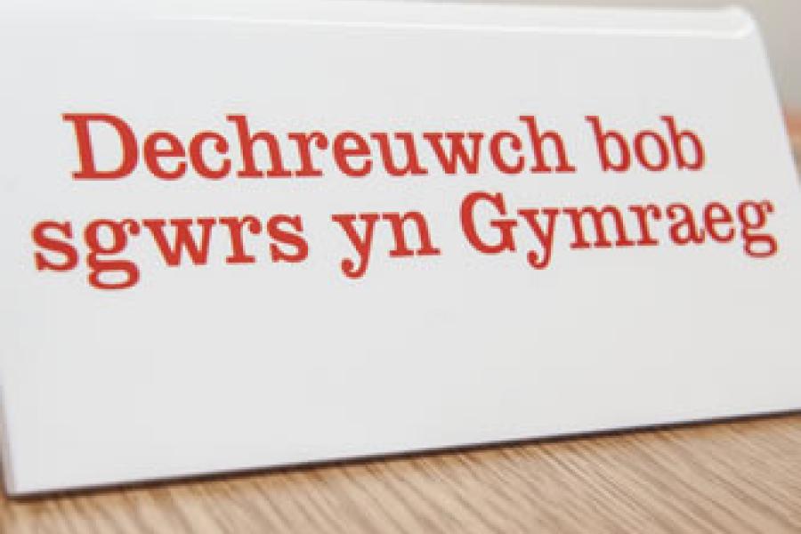 Arwydd 'Dechreuwch bob sgwrs yn Gymraeg'