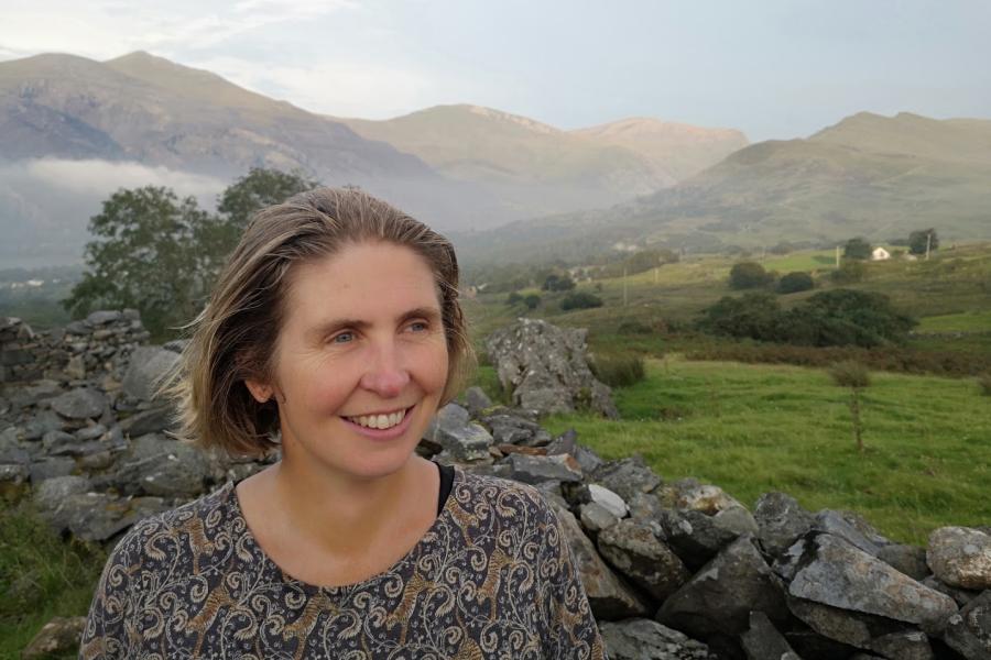 Woman looks to the right with mountain backdrop