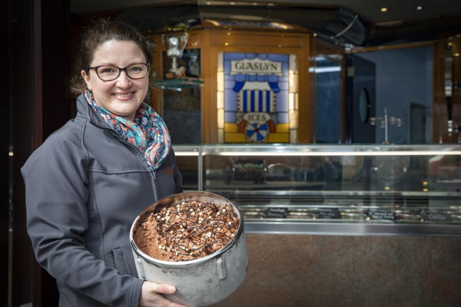 Young woman  holds large tub of chocolate ice cream