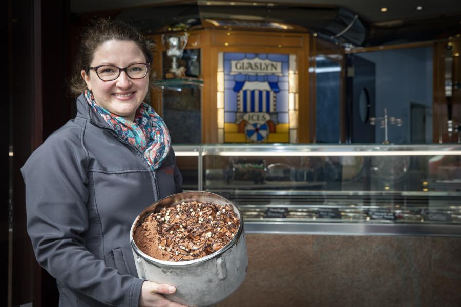Young woman holds large tub of chocolate ice cream