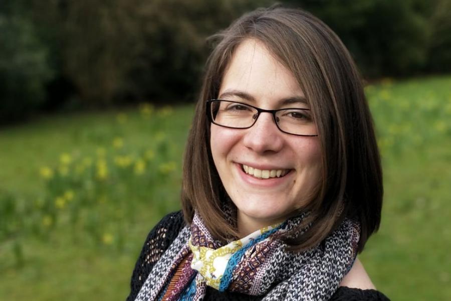 A young woman wearing spectacles looks into the camera