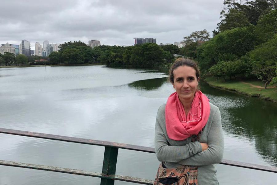 woman looks towards camera with water and cityscape behind