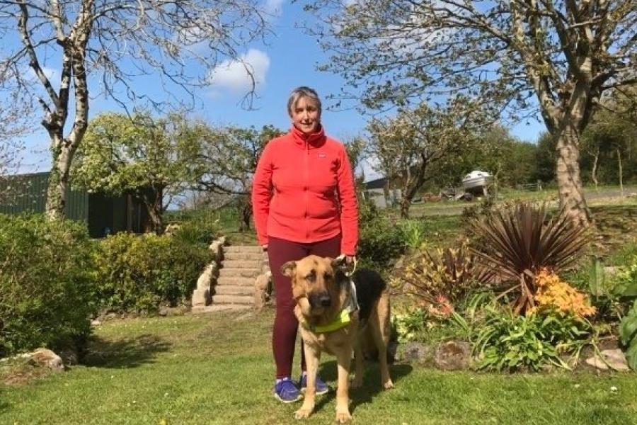 Woman in red top in a garden with guide dog