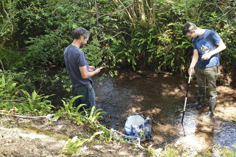 Dan Aberg and Tim Banton collecting water samples in the Whitelake river, while nearby, festival goers  had been enjoying Glastonbury Festival back in 2019.