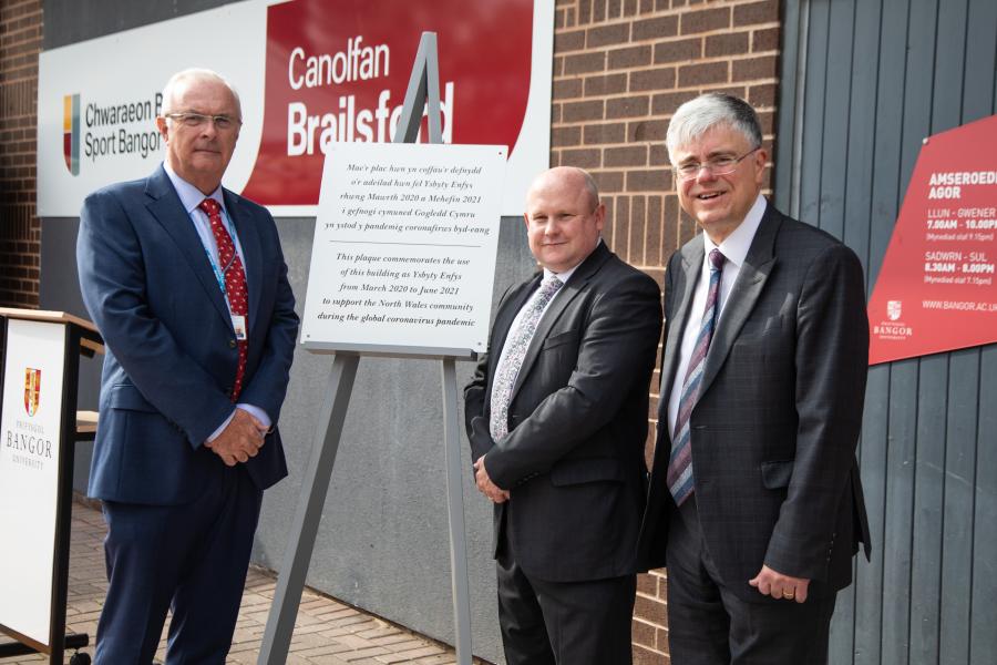  three people and a plaque outside Canolfan Brailsford