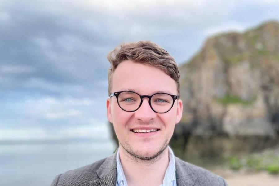 Young spectacled man on out of focus beach