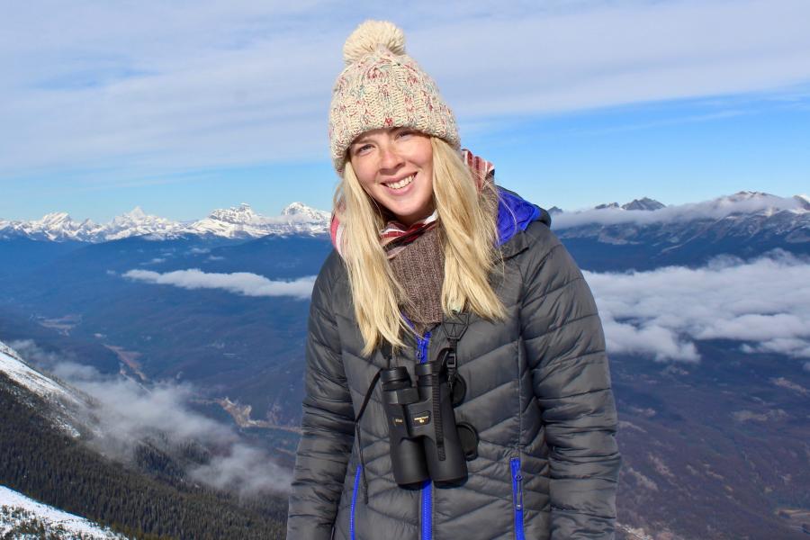 Girl with coat bobble hat and binoculars looks to camera